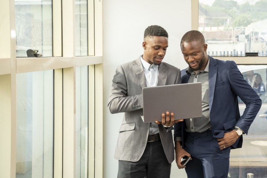 Young black businessmen standing together holding a laptop, disc